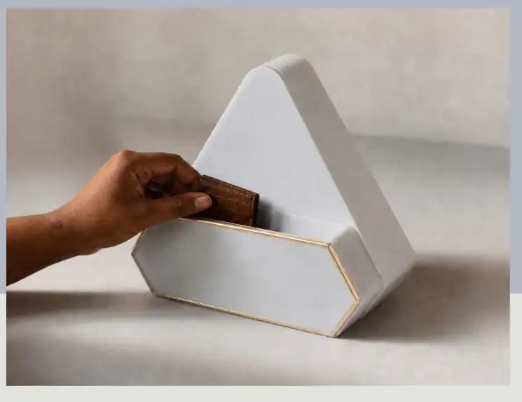 A hand placing a wallet into the open storage compartment of the device.